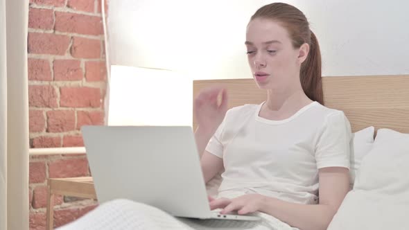 Redhead Young Woman Working on Laptop and Having Headache in Bed