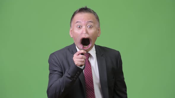 Mature Japanese Businessman Using Magnifying Glass