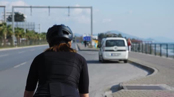 Woman riding bicycle on city street at sunny summer day. 