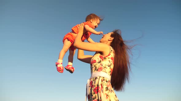 Mother Throw Her Daughter Up To Blu Sky. Slow Motion Filming. Mom Plays with Small Child in Her Arms