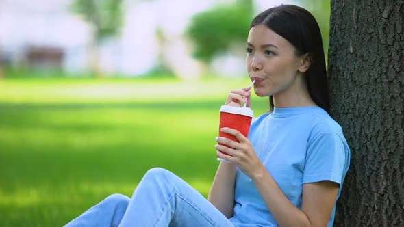 Happy Female Drinking Lemonade Through Straw Sitting Garden Tree, Refreshment
