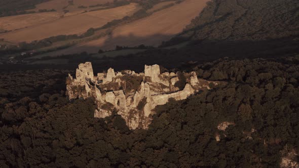 Aerial shot of Gymes Castle ruins lit by last beams of sunset