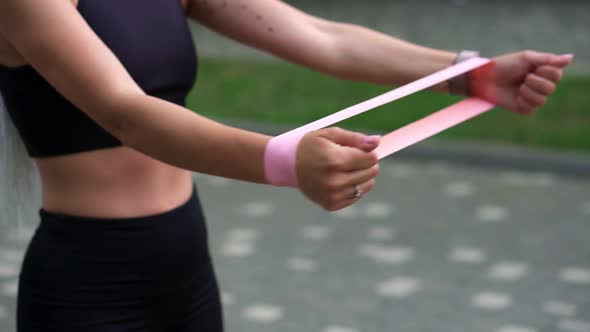 Unrecognizable Athletic Girl Engaged in Fitness Wearing Black Sportswear Exercising with a Rubber