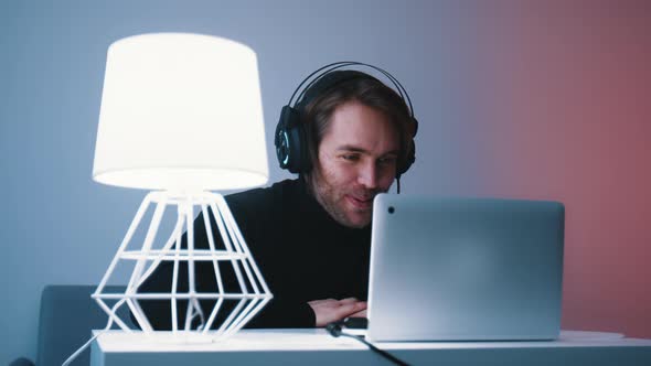 Young Caucasian Bearded Man with Headset Having Video Call on His Laptop