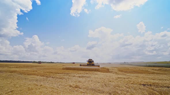 Grain harvesting combine. Landscape of endless fields under blue sky with clouds