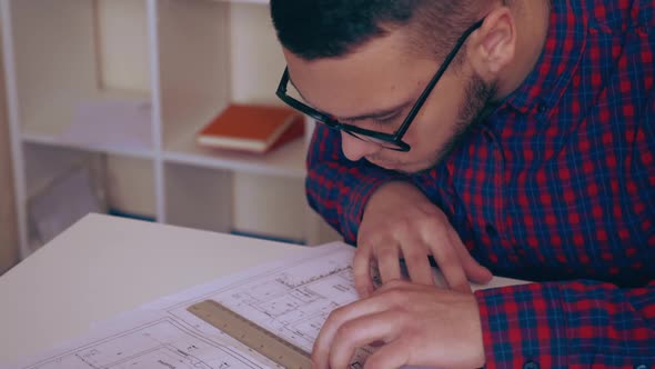 Engineer Sitting at the Workspace Checking Building Plan