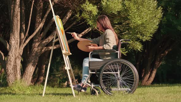 A Disabled Woman in a Wheelchair Draws a Picture in the Park in Sunny Summer Weather