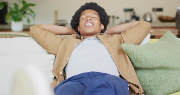 Happy african american man resting and relaxing, siting on the couch