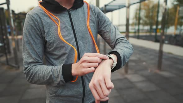 Man Measuring Pulse on Sports Watch During Training Jumping to Ropes Outdoors