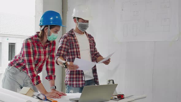 Two Construction worker engineers talking about blueprints at construction site