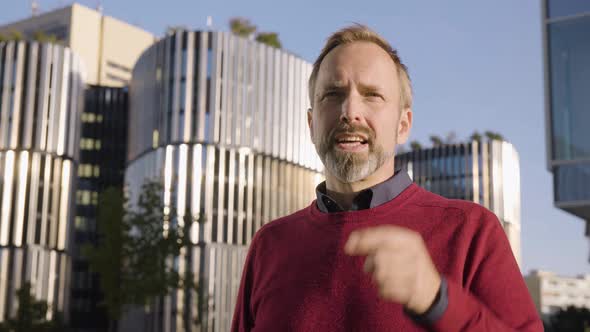 A Middleaged Handsome Caucasian Man Talks to Someone Off Camera in an Urban Area