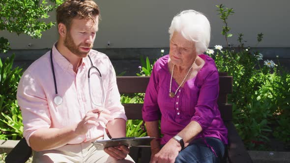 Doctor with a senior woman in the park of a retirement home