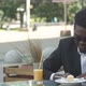 Relaxed Carefree Young Afro American Man in Stylish Eyewear Sitting Alone at Cafe Table, Using Smart - VideoHive Item for Sale