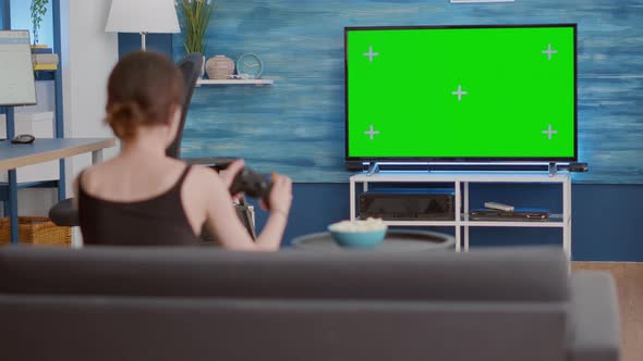 Static Tripod Shot of Gamer Girl Holding Wireless Gamepad Playing Action Console Video Game on Green