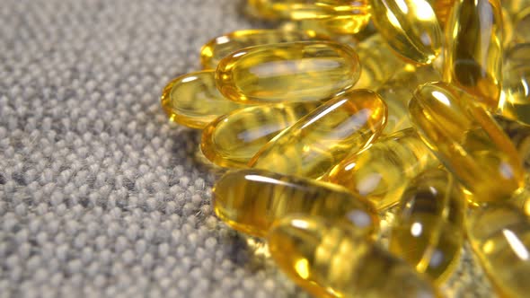 Yellow translucent Omega 3 capsules with fish oil supplement on rustic jute cloth