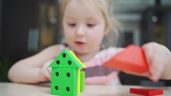 a Cute Little Girl Builds Houses From a Colorful Wooden Construction Set