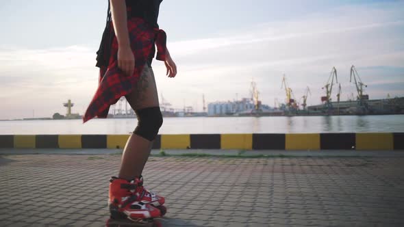 Young Stylish Funky Girl with Green Hair Riding Roller Skates and Dancing Near Sea Port During