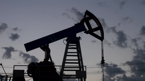 Oil Rig Stands in a Field at Sunset and Extracts Minerals