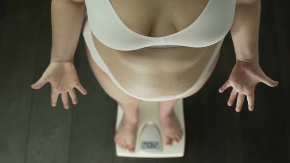 Obese Woman Standing on Scales Desperately Gesturing Hands, Fat Belly, Top View