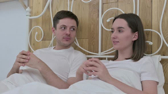 Attractive Young Couple Sitting in Bed and Talking 