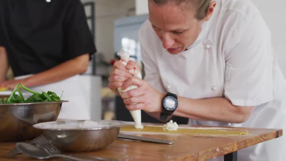 Caucasian female chef teaching diverse group preparing dishes and smiling