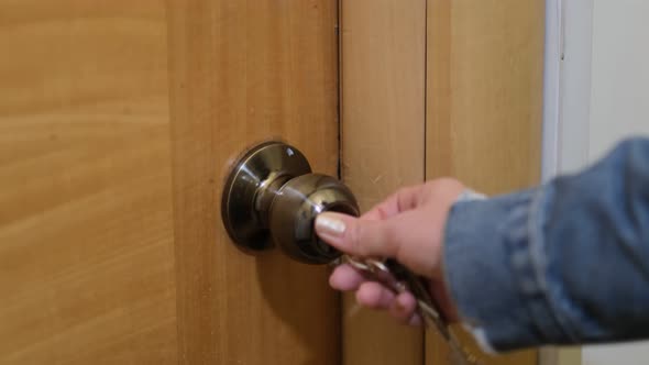 Woman Using a Key to Open the Lock of the Front Door