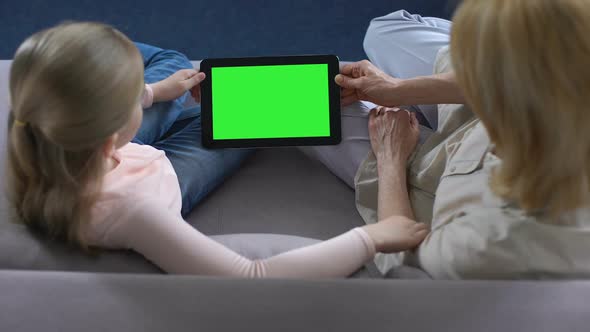 Grandmother and Little Female Grandkid Holding Tablet With Green Screen, Apps