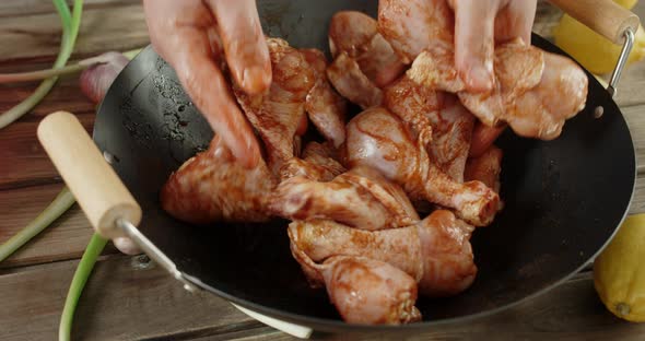 Men's Hands Stir Raw Chicken Drumstick with the Spices.