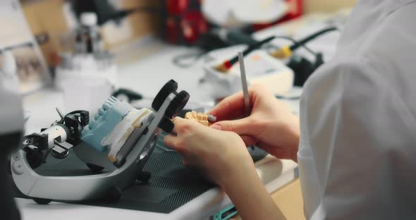 Dental Technician Woman Works with Special Tools with Plaster Models of the Jaw