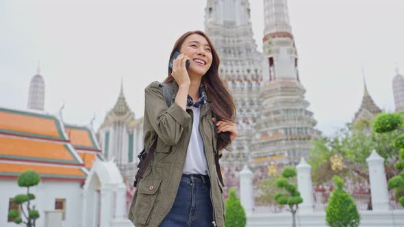 Asian attractive woman backpacker talking on phone while walk in city.