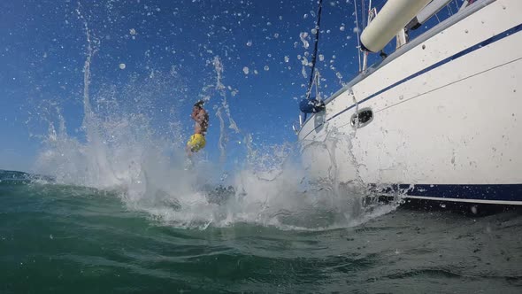 Happy friends diving from sailing boat into the sea