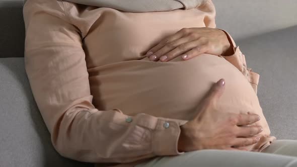 Relaxed Woman in Headscarf Stroking Belly With Love, Pregnancy and Motherhood