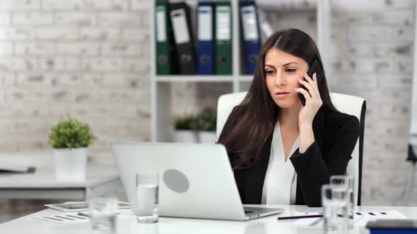 Adorable Smiling Businesswoman Talking on Smartphone Looking at Screen of Laptop Pc Medium Shot