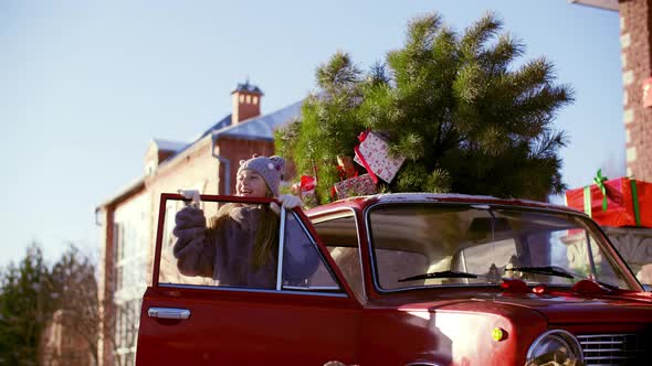 Cute Girl Laughing Near Car with Christmas Tree and Gift Boxes