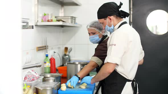 Cooking. the Chef, in Protective Mask and Gloves, Is Cutting Boiled Potatoes on Cooking Board