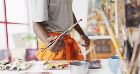 Midsection of african american male painter painting on canvas in artist studio