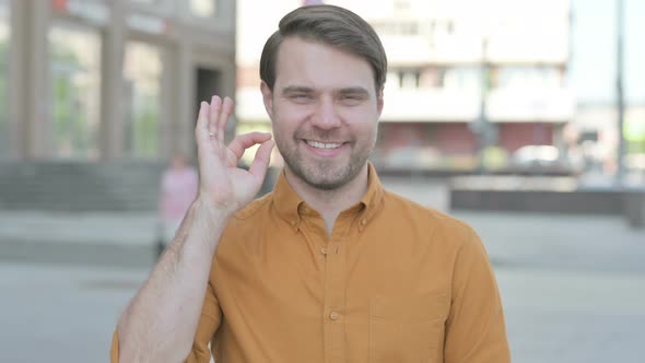 Young Man showing Ok Sign with Finger Outdoor