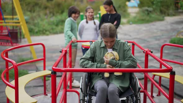 Portrait of Sad Caucasian Disabled Girl in Wheelchair Hugging Toy and Looking at Camera in Slow