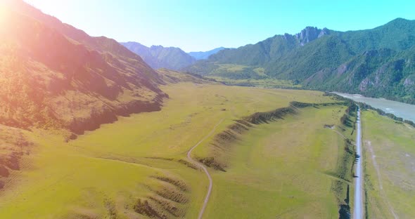 Aerial Rural Mountain Road and Meadow at Sunny Summer Morning. Asphalt Highway and River.