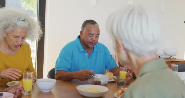 Happy senior diverse people having breakfast at retirement home