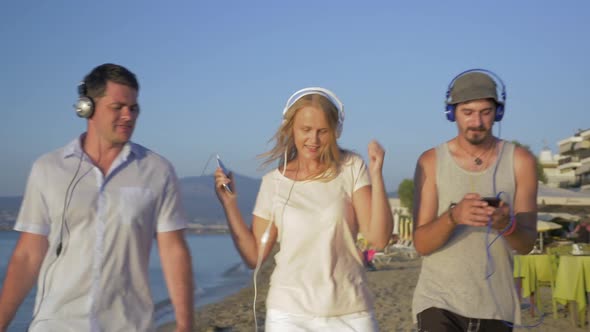 Three Friends Walking with Music on the Beach