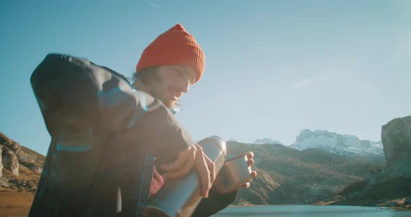 Man on Springtime Journey Take Break Pouring and Drinking Hot Drink on Mountain