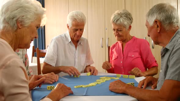 Senior friends talking while playing dominos