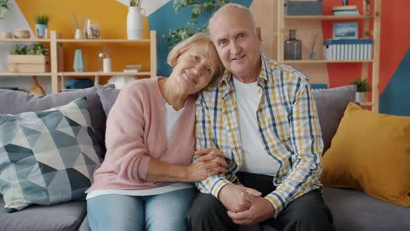 Portrait of Couple Senior Man and Woman Smiling Looking at Camera at Home on Sofa