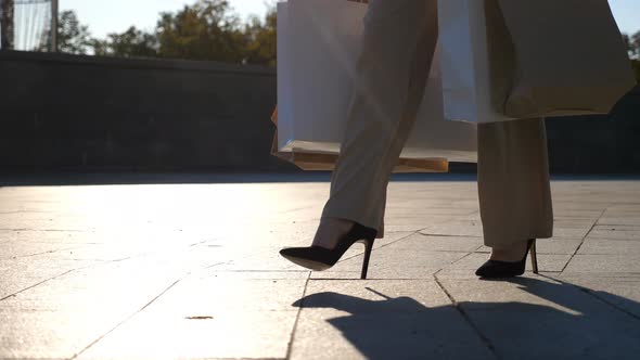 Young Female Customer Holds Shopping Bags Walking at Sidewalk After Purchases