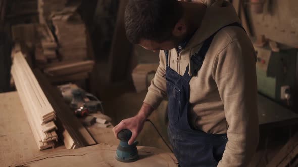 The Joiner Finishes Grinding the Piece of Wood Turns Off the Grinder and Checks the Surface for