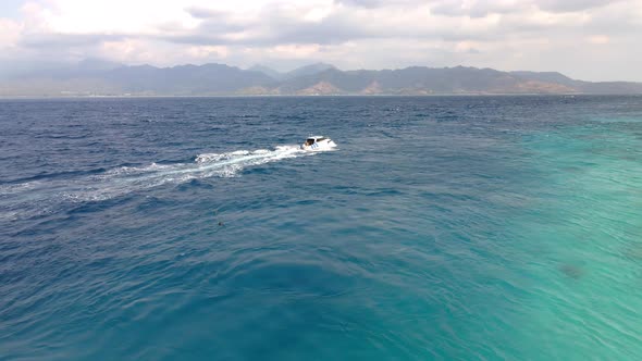 Tracking shot of speedboat riding on clear ocean during sunlight in Gili Meno Island,Indonesia.