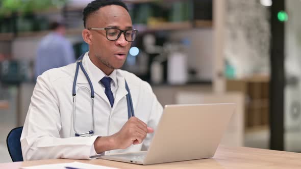 Serious African Male Doctor Doing Video Call on Laptop in Office 