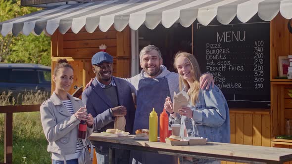 Group of happy people standing near street food trailer