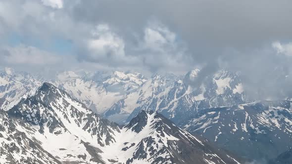 Air Flight Through Mountain Clouds Over Beautiful Snowcapped Peaks of Mountains and Glaciers